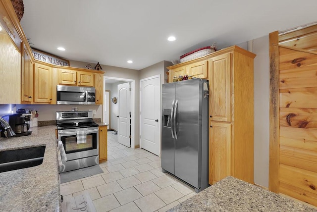 kitchen with light brown cabinetry, light stone countertops, sink, and stainless steel appliances