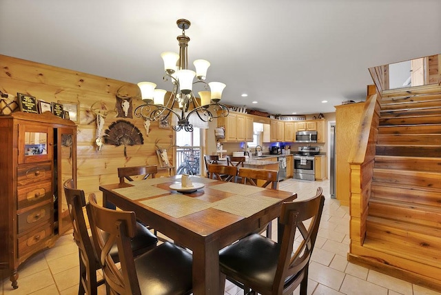 dining room with wood walls, light tile patterned floors, sink, and an inviting chandelier