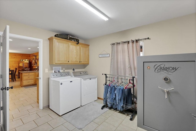 laundry room featuring wooden walls, cabinets, and washer and dryer