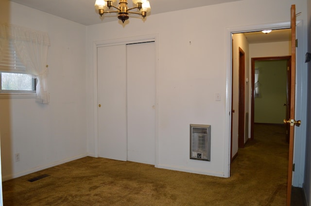 unfurnished bedroom with dark colored carpet, heating unit, a closet, and a notable chandelier