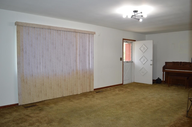 carpeted spare room with an inviting chandelier