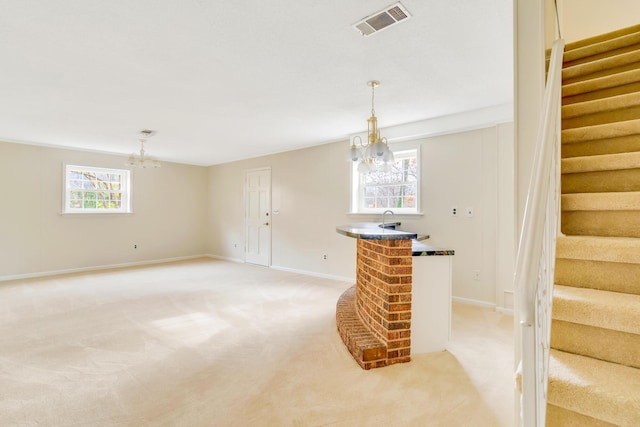 unfurnished living room featuring a notable chandelier and light carpet