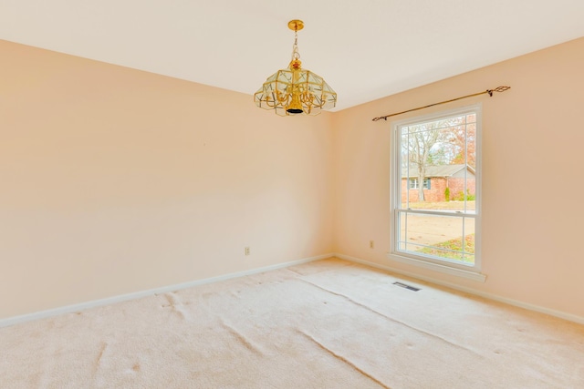 carpeted spare room featuring a notable chandelier