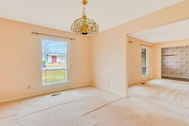 carpeted empty room featuring a chandelier