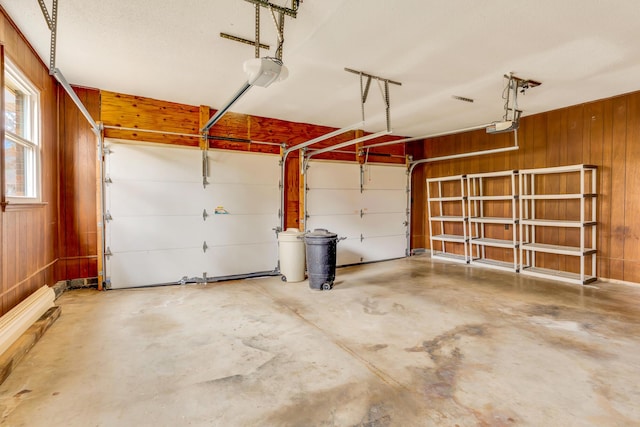 garage with a garage door opener and wood walls