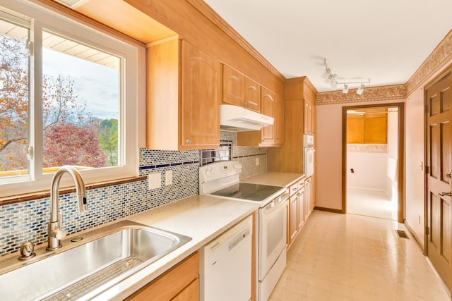 kitchen with backsplash, white appliances, sink, and rail lighting