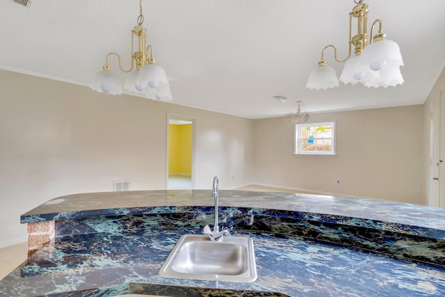 interior space with decorative light fixtures, ornamental molding, sink, and dark stone counters