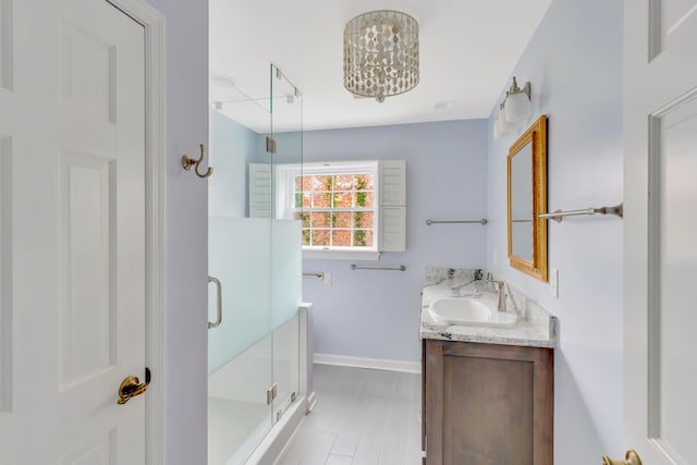 bathroom featuring a notable chandelier, vanity, and walk in shower