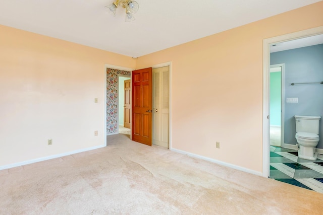 unfurnished bedroom featuring ensuite bathroom and light colored carpet