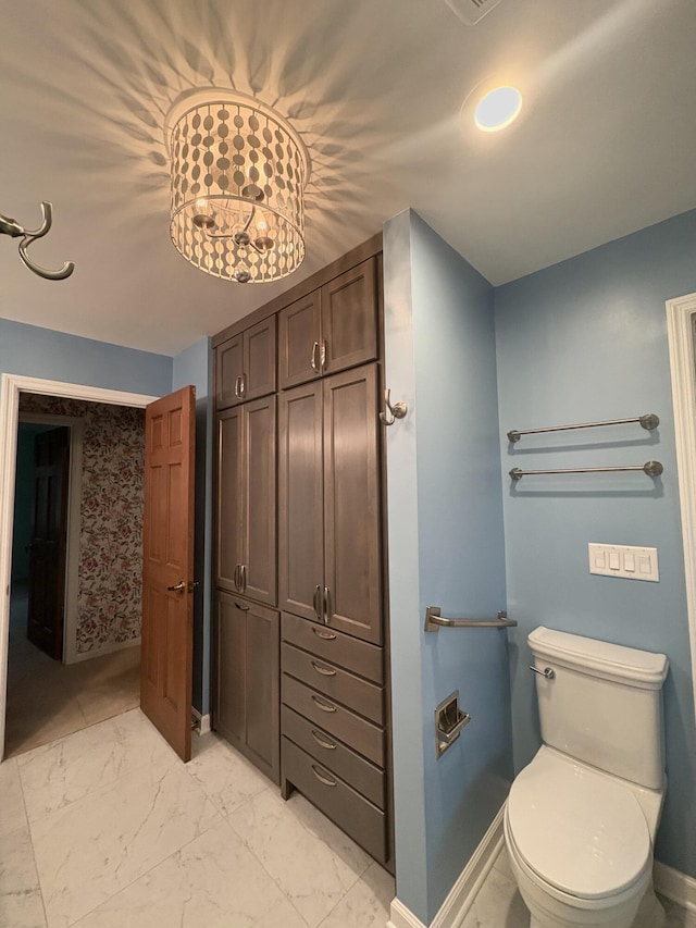 bathroom with an inviting chandelier and toilet