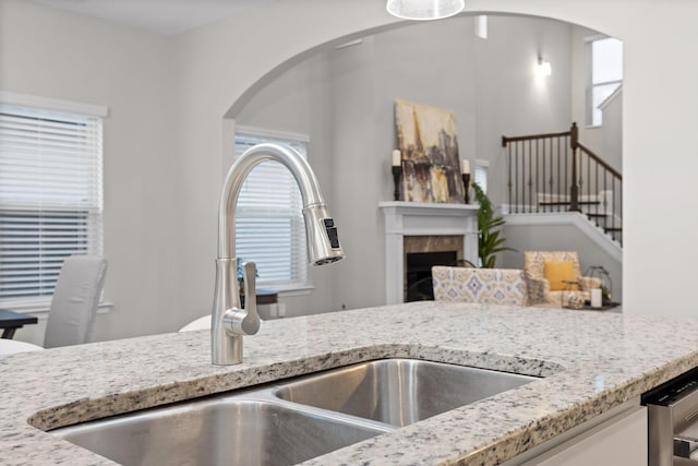 kitchen featuring sink, a tile fireplace, and light stone countertops