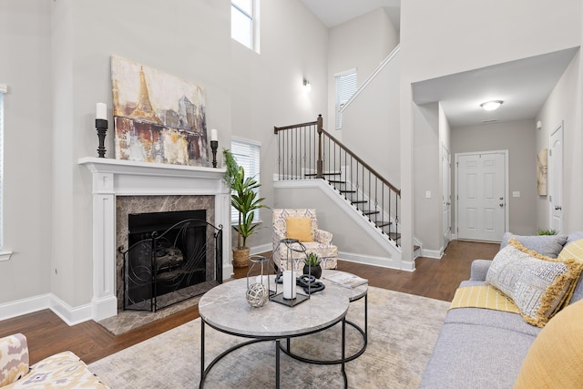 living room with dark hardwood / wood-style flooring, a fireplace, a high ceiling, and plenty of natural light