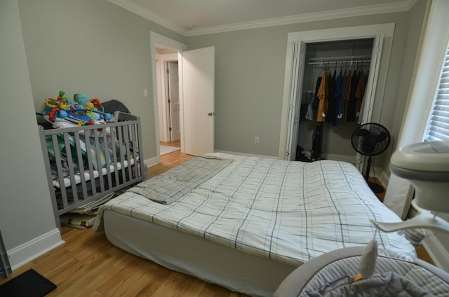 bedroom with light hardwood / wood-style floors, crown molding, and a closet