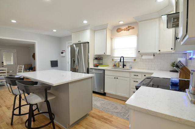 kitchen with a center island, sink, light hardwood / wood-style flooring, white cabinetry, and stainless steel appliances