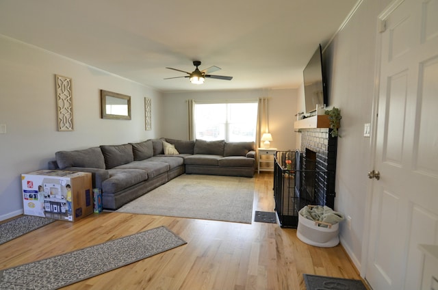 living room featuring hardwood / wood-style floors, ceiling fan, and a brick fireplace