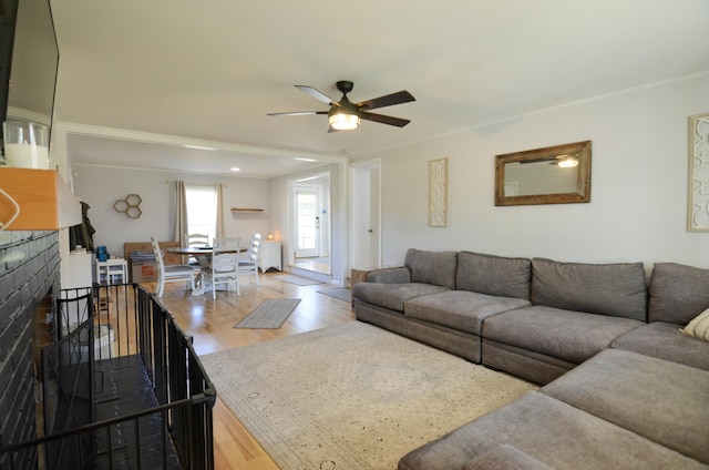 living room featuring ceiling fan, wood-type flooring, and a tile fireplace