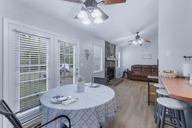 dining area with light wood-type flooring, vaulted ceiling, and ceiling fan