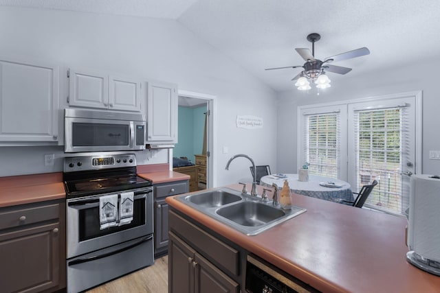 kitchen featuring stainless steel appliances, sink, light hardwood / wood-style floors, white cabinetry, and lofted ceiling