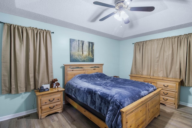 bedroom featuring a textured ceiling, light wood-type flooring, and ceiling fan