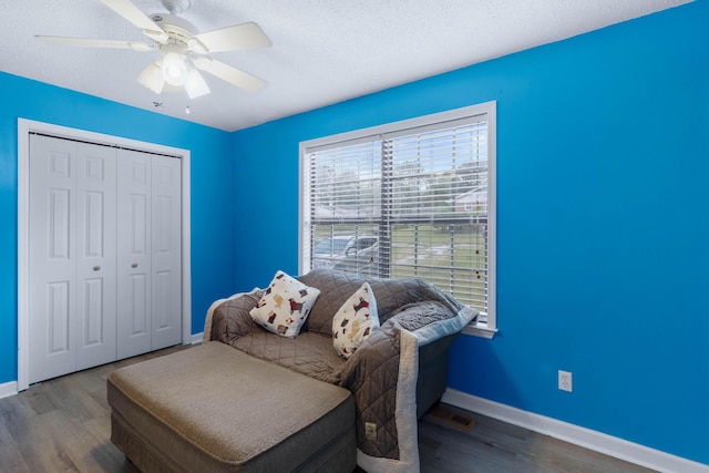 living area featuring ceiling fan, wood-type flooring, and a textured ceiling