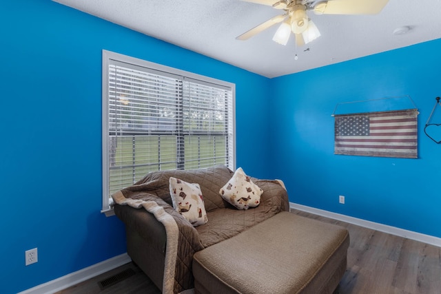 living area with ceiling fan, hardwood / wood-style floors, and a textured ceiling