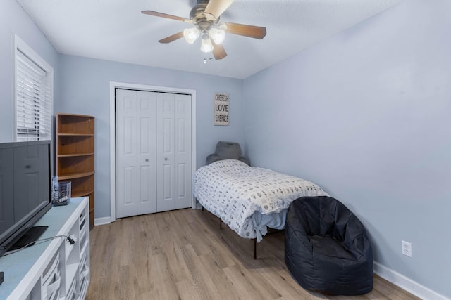 bedroom with a closet, light hardwood / wood-style flooring, and ceiling fan