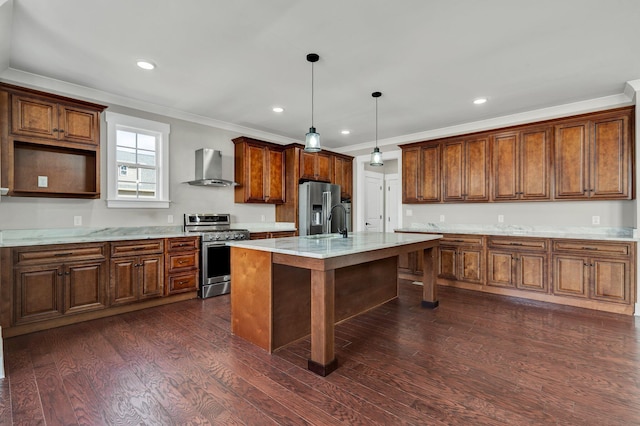 kitchen with pendant lighting, a center island with sink, wall chimney range hood, appliances with stainless steel finishes, and dark hardwood / wood-style flooring