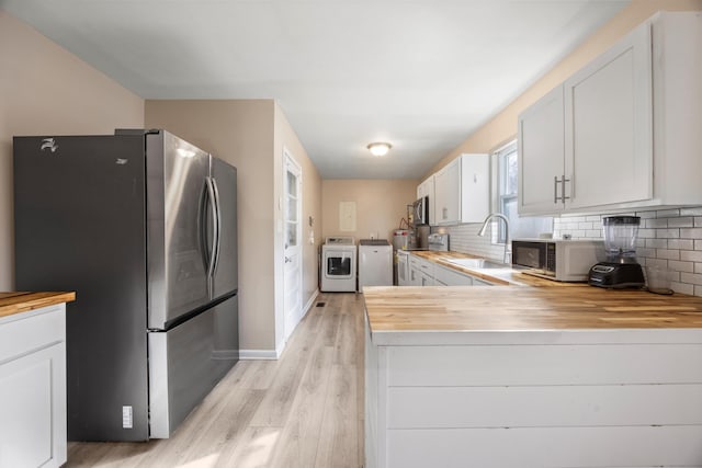 kitchen with sink, backsplash, kitchen peninsula, white cabinets, and appliances with stainless steel finishes