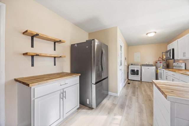 kitchen with white cabinets, butcher block counters, appliances with stainless steel finishes, and washing machine and clothes dryer