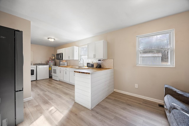 kitchen featuring wooden counters, backsplash, stainless steel appliances, washing machine and clothes dryer, and white cabinetry