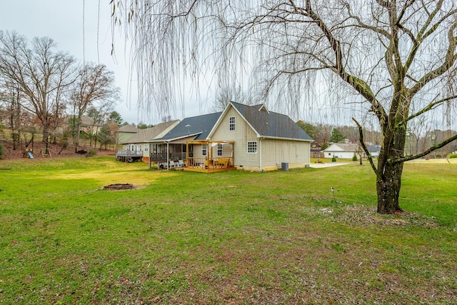 rear view of property with an outdoor fire pit, a deck, and a yard