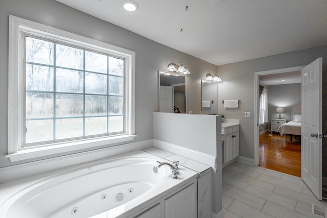 bathroom featuring a healthy amount of sunlight, tile patterned floors, a washtub, and vanity