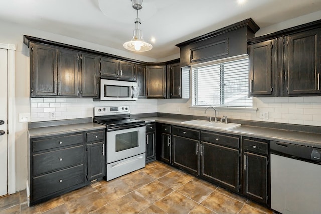 kitchen with appliances with stainless steel finishes, tasteful backsplash, dark brown cabinetry, sink, and decorative light fixtures