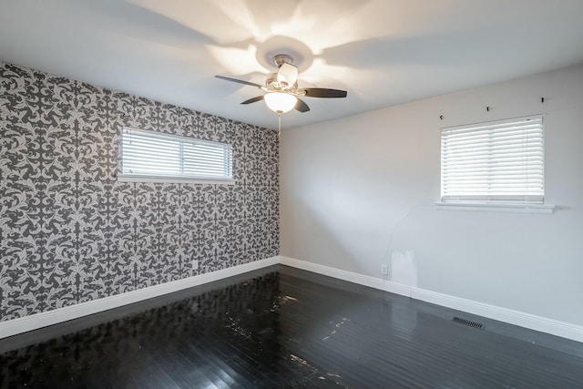 unfurnished room with ceiling fan, dark wood-type flooring, and a healthy amount of sunlight