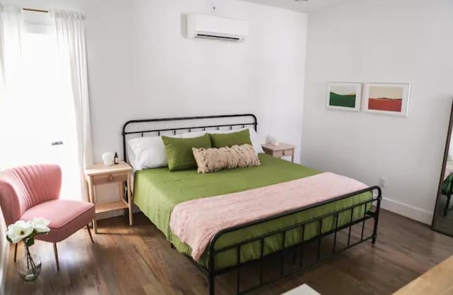 bedroom featuring dark hardwood / wood-style floors and a wall unit AC