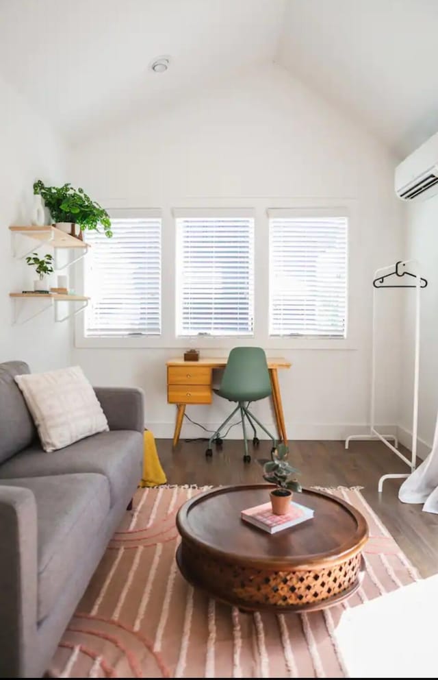 living room featuring plenty of natural light, dark hardwood / wood-style floors, lofted ceiling, and an AC wall unit