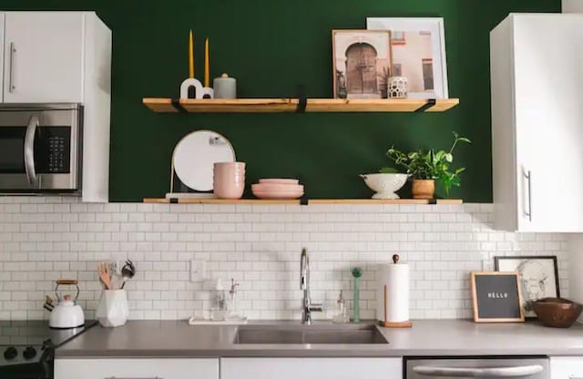 kitchen featuring decorative backsplash, sink, white cabinets, and stainless steel appliances