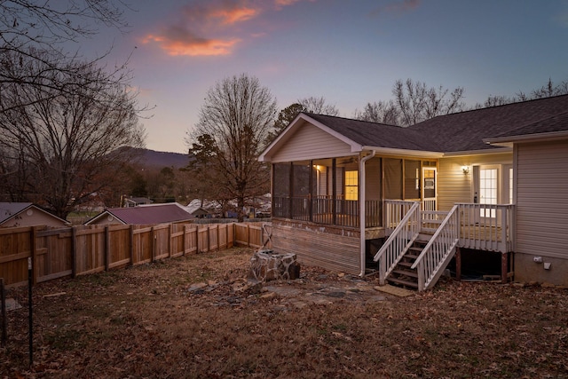 back house at dusk with a sunroom and a deck with mountain view