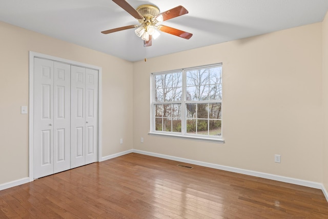 unfurnished bedroom with ceiling fan, wood-type flooring, and a closet