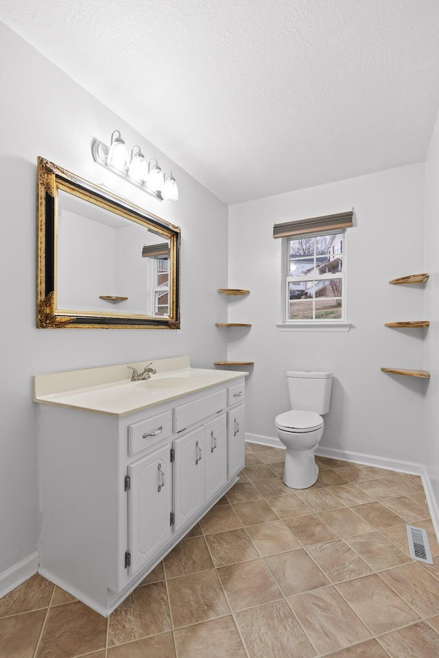 bathroom featuring a textured ceiling, vanity, and toilet