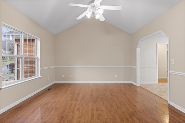 empty room with ceiling fan, vaulted ceiling, and light wood-type flooring