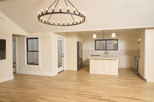 kitchen with sink, white cabinetry, light wood-type flooring, appliances with stainless steel finishes, and pendant lighting