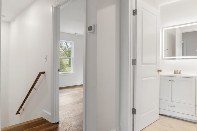 hallway with sink and light hardwood / wood-style flooring