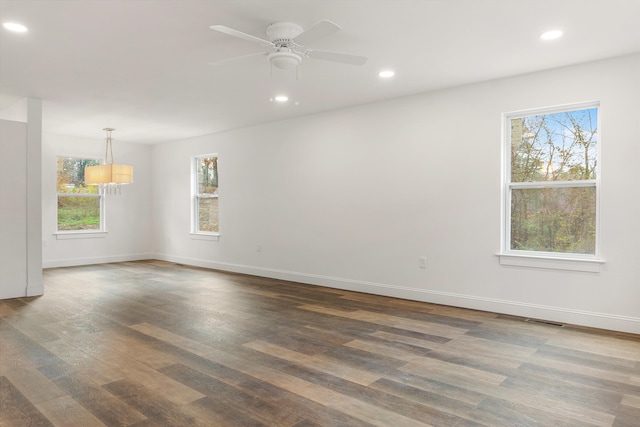 spare room featuring dark hardwood / wood-style flooring and ceiling fan with notable chandelier