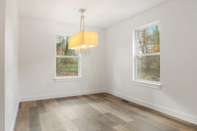 unfurnished dining area featuring wood-type flooring and a chandelier