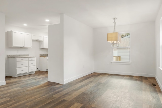 unfurnished dining area featuring dark wood-type flooring