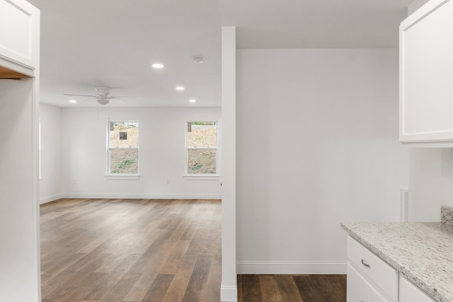 interior space with ceiling fan, white cabinets, light stone countertops, and dark hardwood / wood-style floors