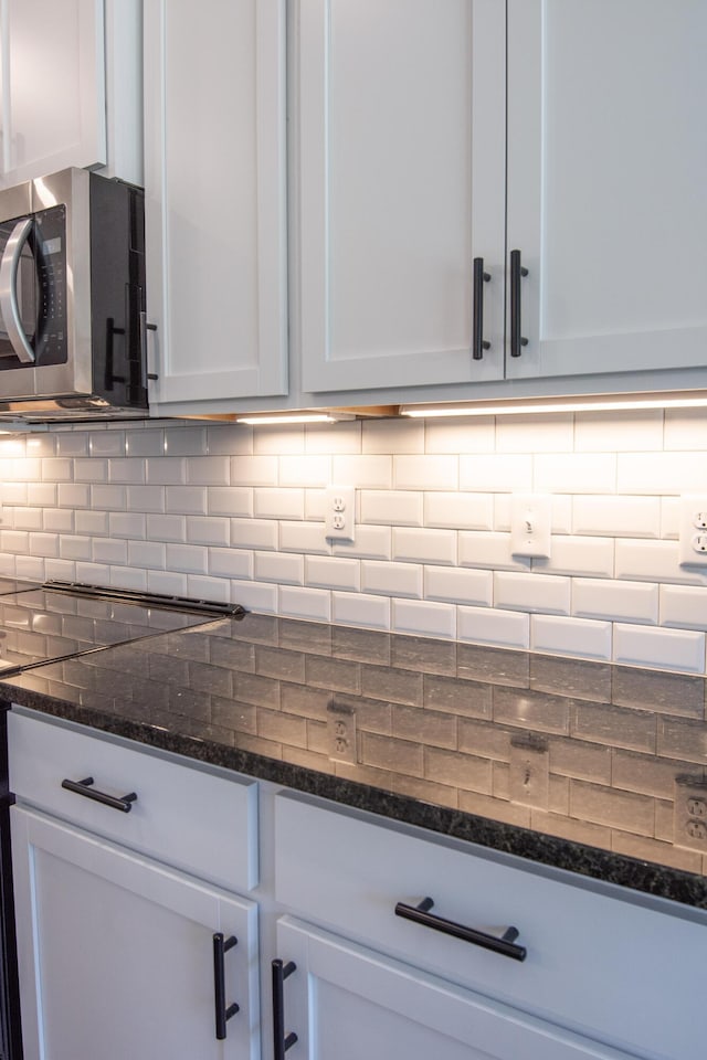 kitchen with white cabinets, backsplash, and dark stone counters