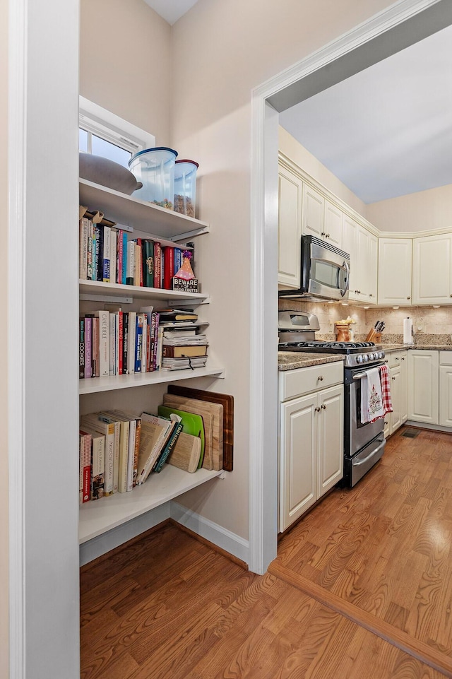 kitchen featuring appliances with stainless steel finishes, light hardwood / wood-style flooring, and decorative backsplash