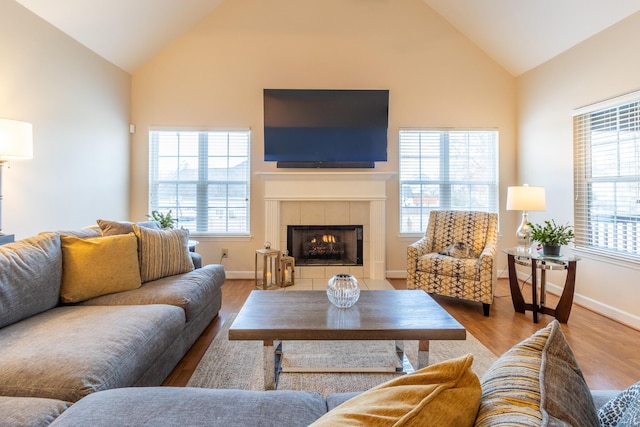 living room with lofted ceiling, a fireplace, light hardwood / wood-style flooring, and a wealth of natural light